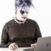 a person in a cat mask sitting in front of a laptop