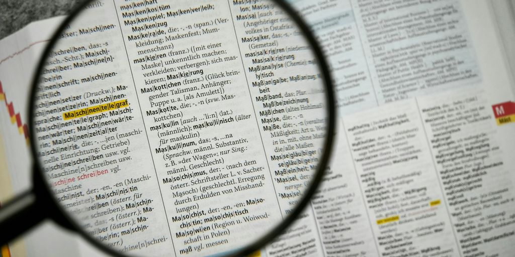 Magnifying glass focuses on a dictionary page.