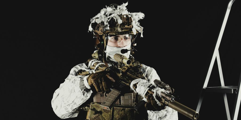 a man dressed in camouflage holding a rifle