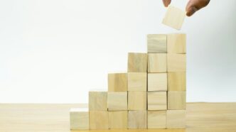 A person placing a piece of wood into a pyramid