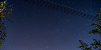 a night sky with stars and a line of power lines