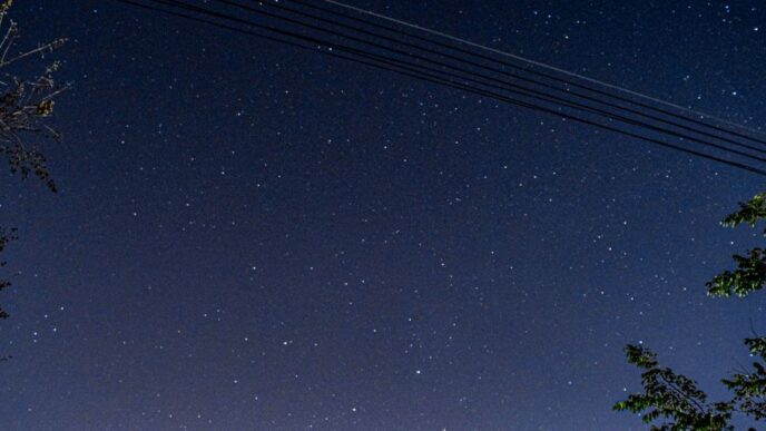 a night sky with stars and a line of power lines