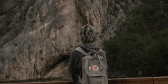A person with a backpack standing on a bridge