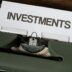 a close up of a typewriter with a paper that reads investments