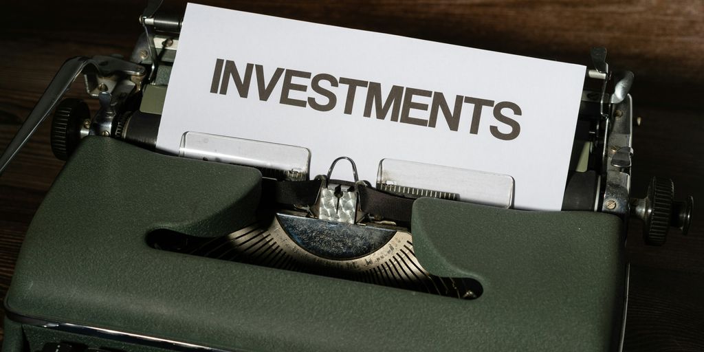 a close up of a typewriter with a paper that reads investments