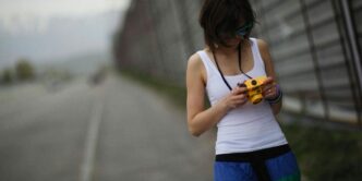 a woman standing on the side of a road looking at a cell phone