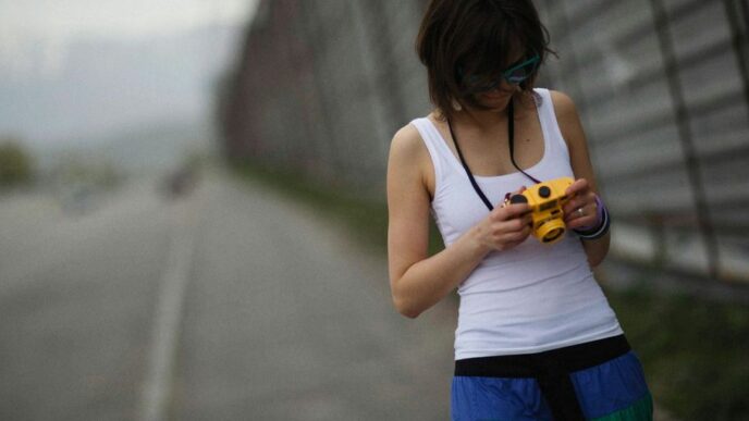 a woman standing on the side of a road looking at a cell phone