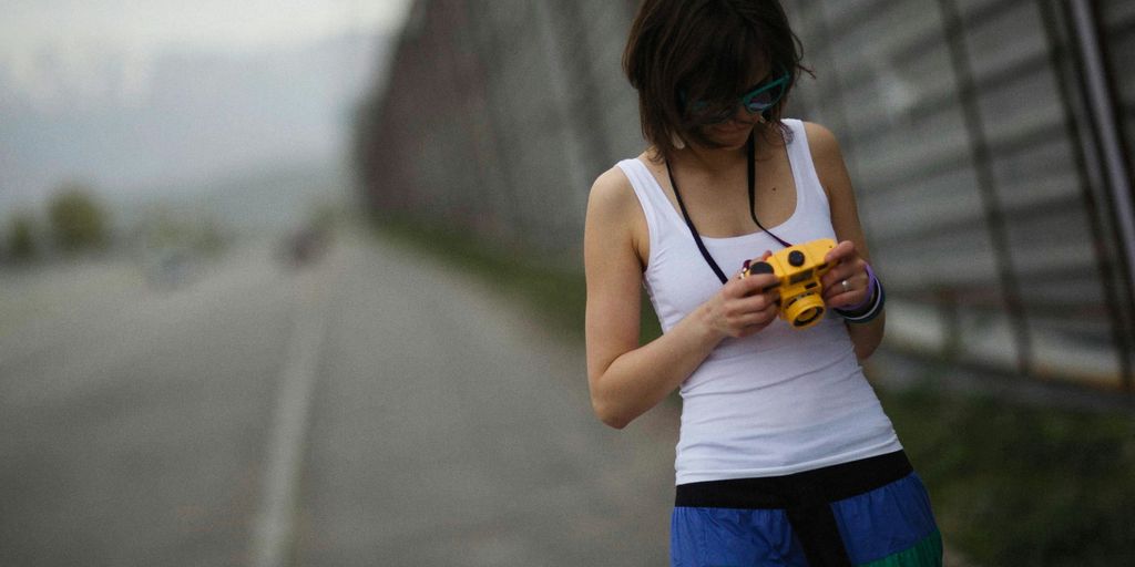 a woman standing on the side of a road looking at a cell phone