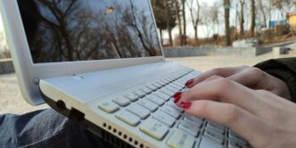 a person typing on a laptop computer outside