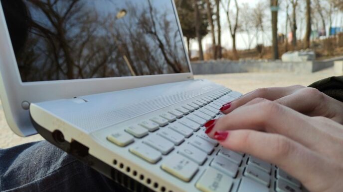 a person typing on a laptop computer outside
