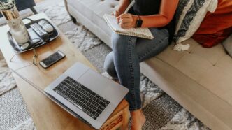 woman in black and white tank top and blue denim jeans sitting on white couch