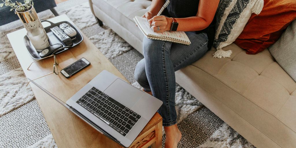 woman in black and white tank top and blue denim jeans sitting on white couch