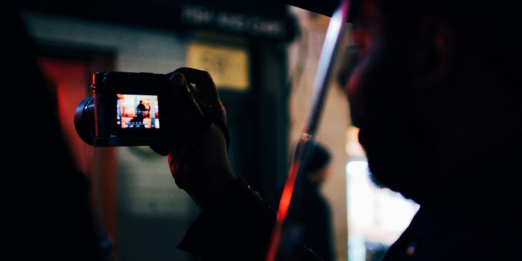 person under the umbrella holding digital camera