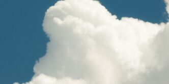 a jet flying through a cloudy blue sky