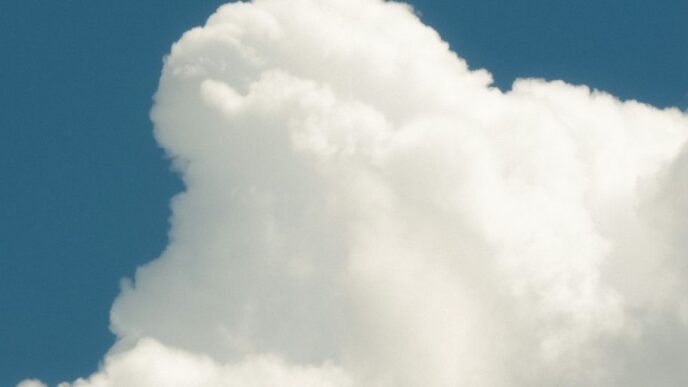 a jet flying through a cloudy blue sky