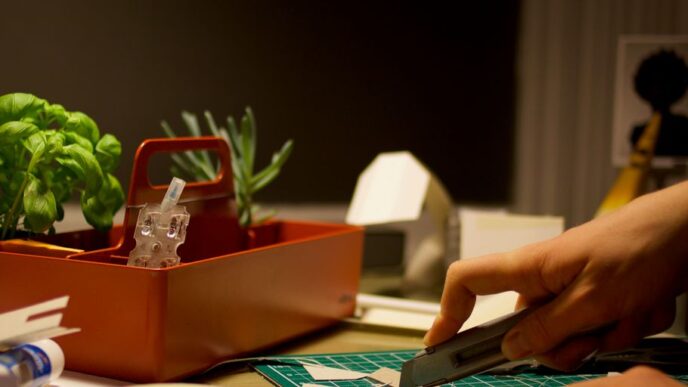person cutting paper beside orange tray