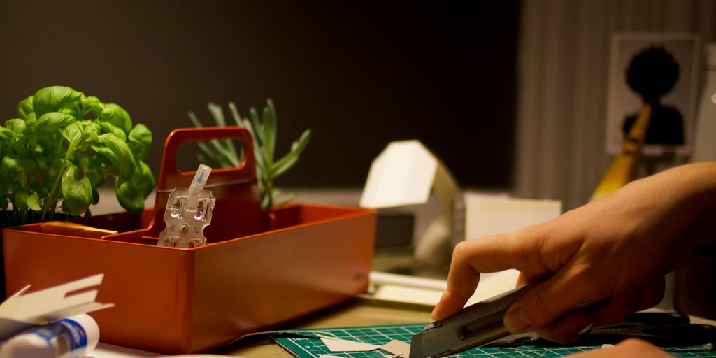 person cutting paper beside orange tray