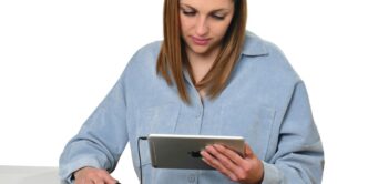 a woman sitting at a table looking at a tablet