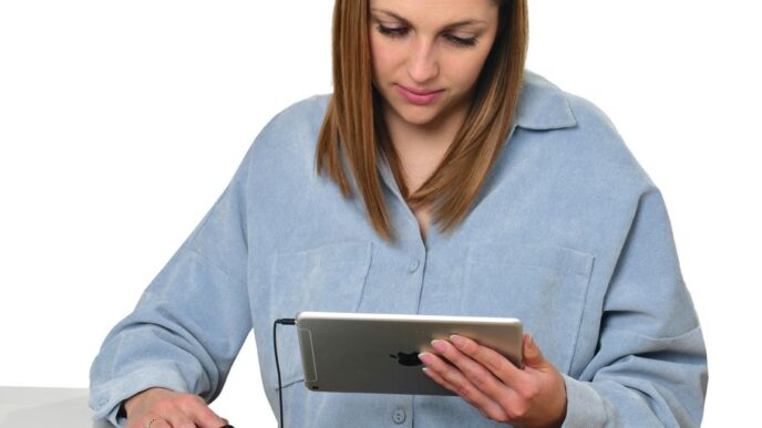 a woman sitting at a table looking at a tablet