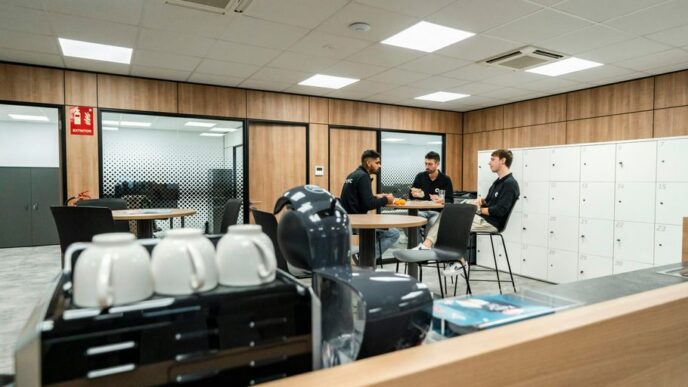 Three people are chatting in a modern office space.
