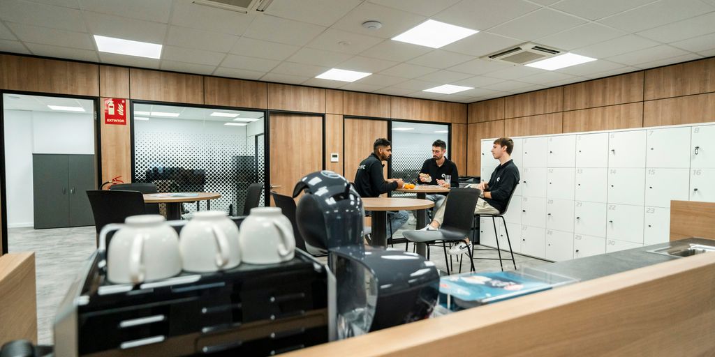 Three people are chatting in a modern office space.