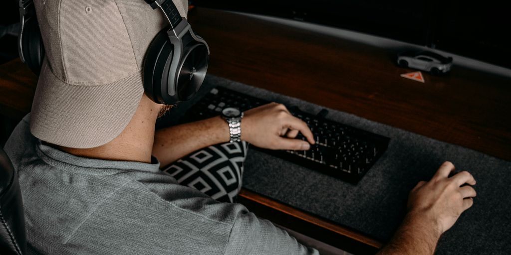 a man wearing headphones and sitting at a desk with a computer