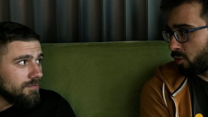 a couple of men sitting on top of a green couch