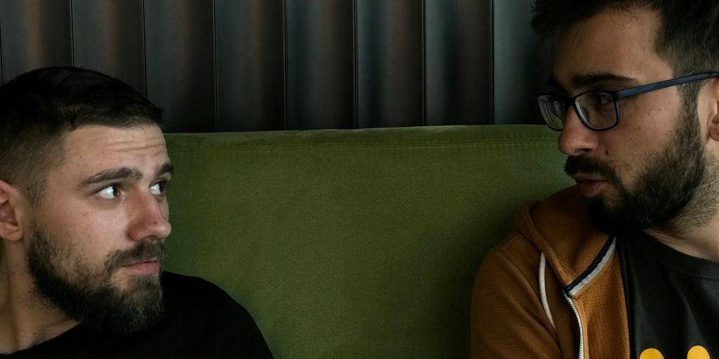 a couple of men sitting on top of a green couch