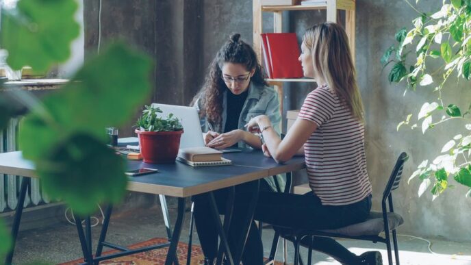 Two women collaborate at a desk in an office.