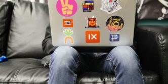 man using silver MacBook sitting on black leather sofa