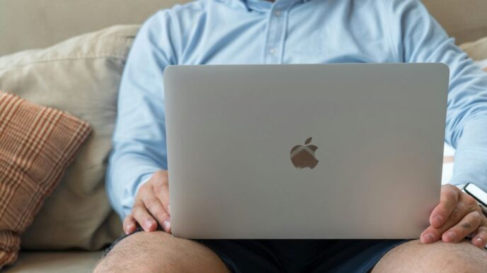 a man sitting on a couch holding a laptop