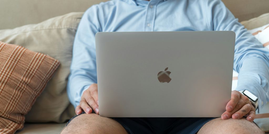 a man sitting on a couch holding a laptop
