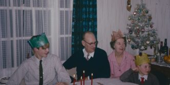 a group of people sitting around a table with a christmas tree
