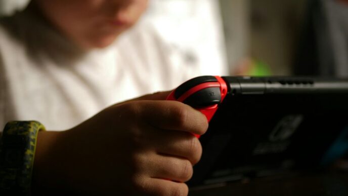 boy in white crew neck t-shirt holding black and red cordless device