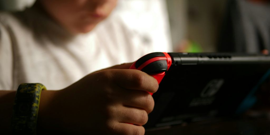boy in white crew neck t-shirt holding black and red cordless device