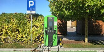 A green gas pump sitting on the side of a road