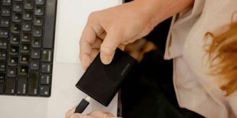 A person holding a cell phone in front of a laptop