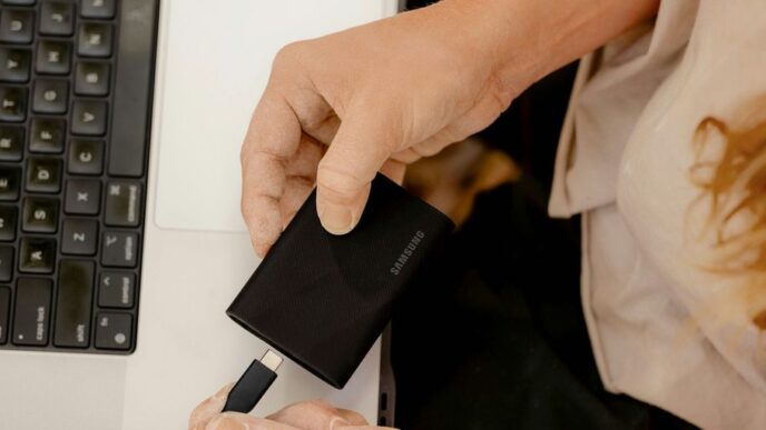 A person holding a cell phone in front of a laptop