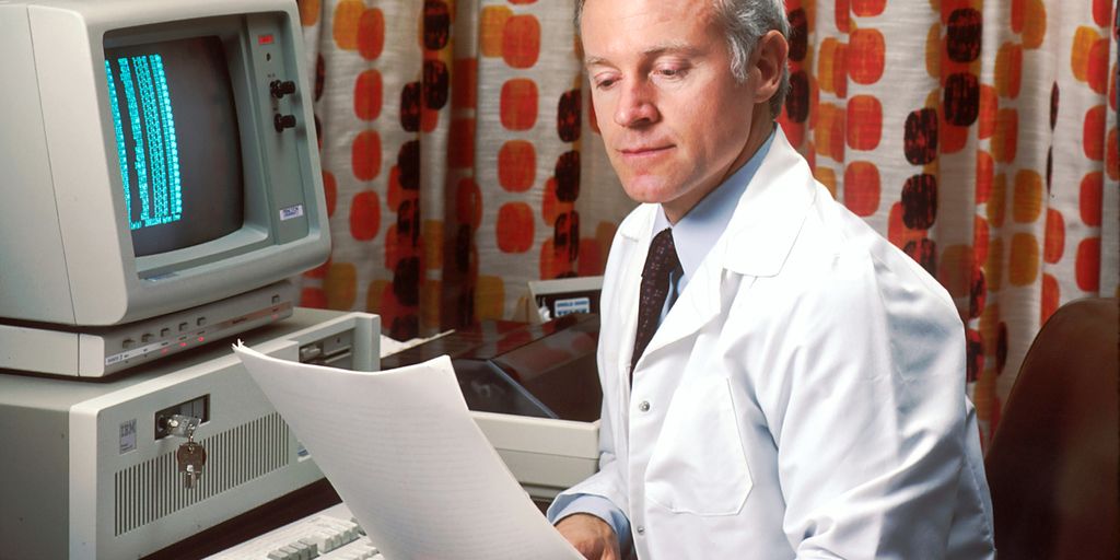 man reading papers in front of computer