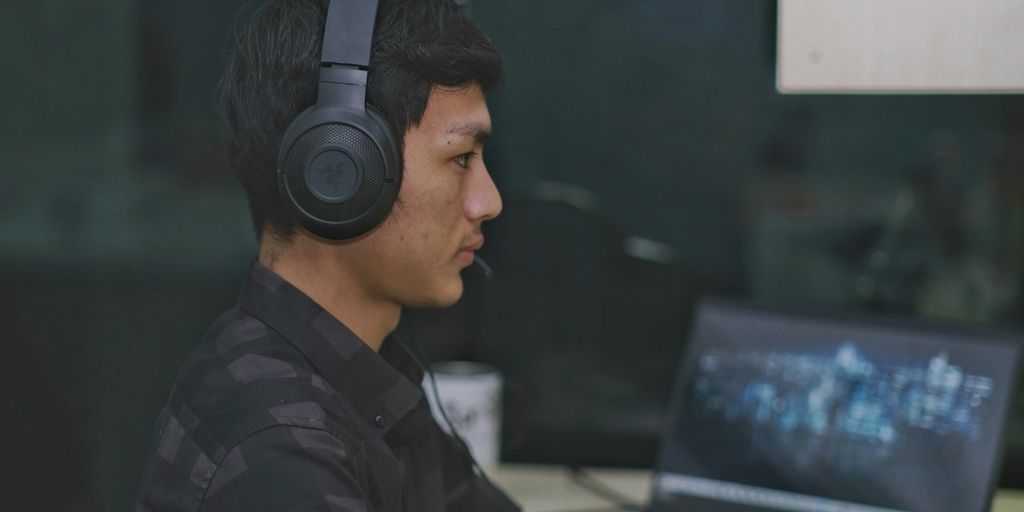 a man wearing headphones is using a laptop