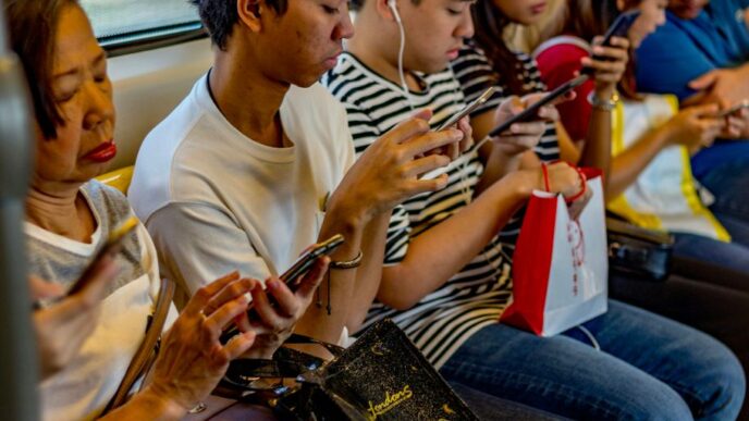 people using smartphones while sitting inside train