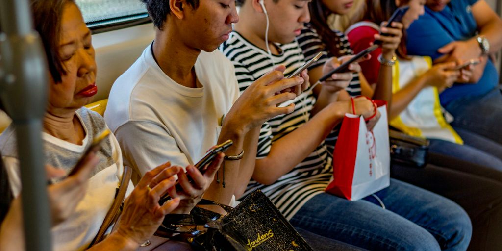 people using smartphones while sitting inside train