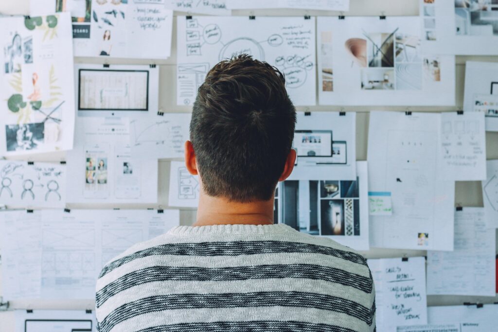 man facing a wall of white papers with illustrations