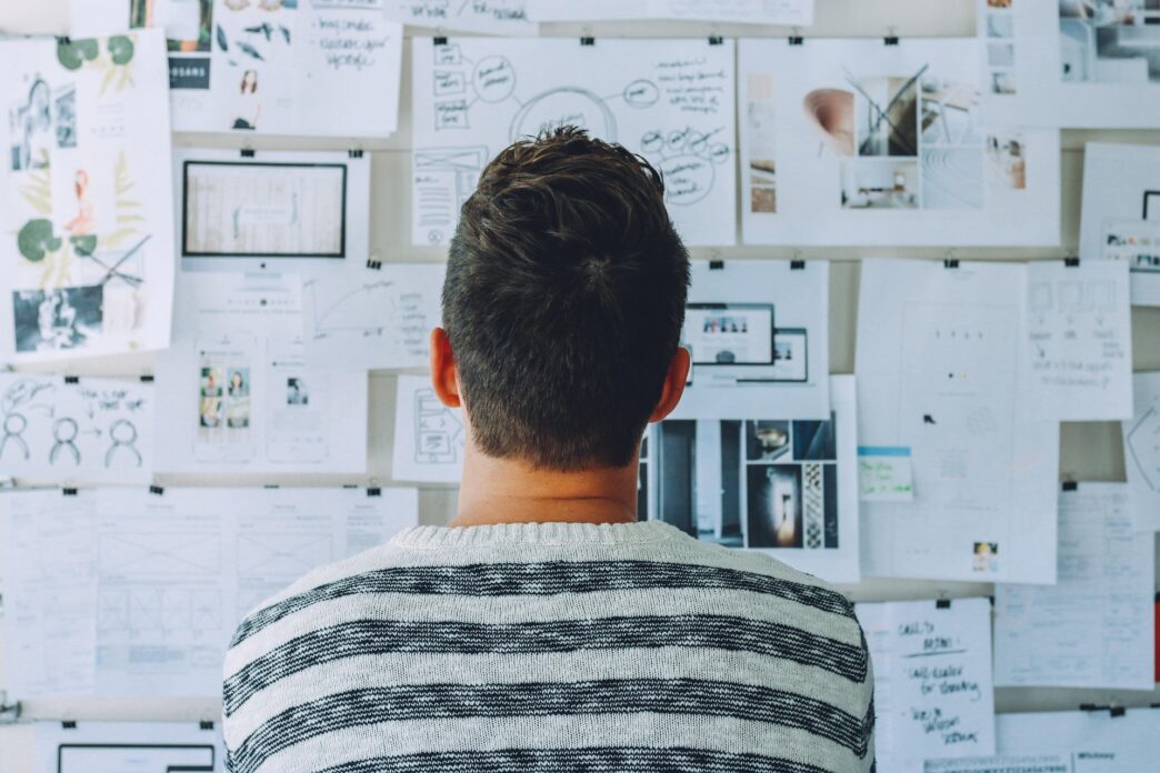 man facing a wall of white papers with illustrations