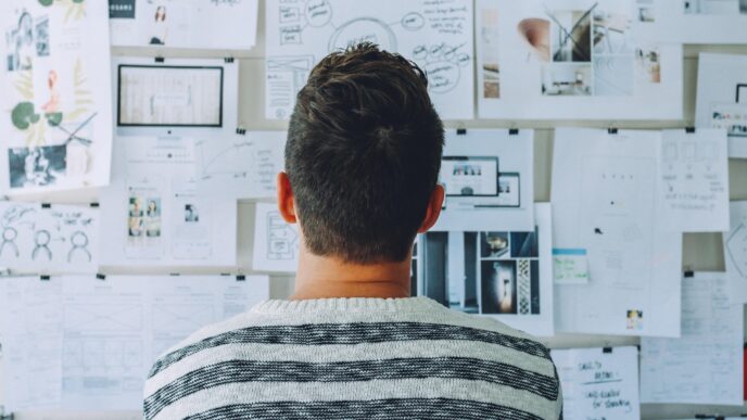 man facing a wall of white papers with illustrations