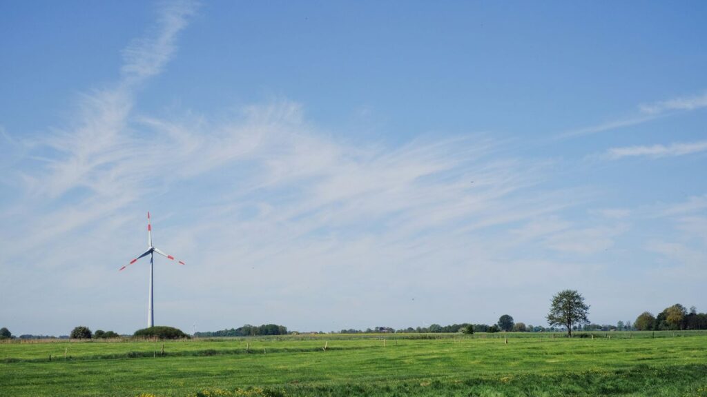 a green field with a windmill in the distance