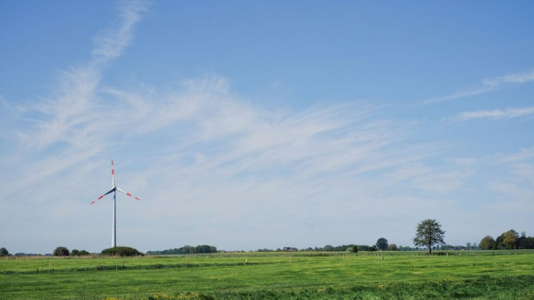 a green field with a windmill in the distance