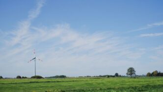 a green field with a windmill in the distance