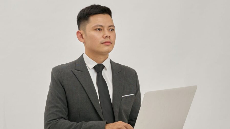 A businessman is holding a laptop and looking up.