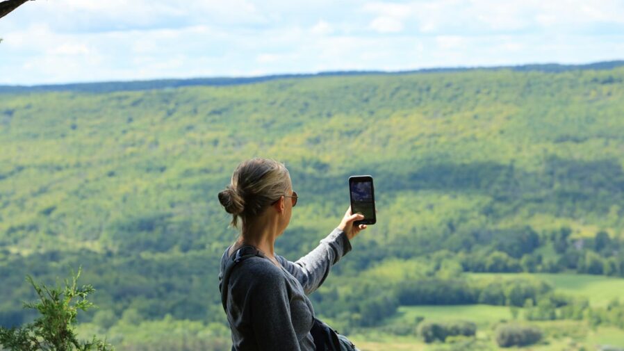woman in black jacket taking photo of green grass field during daytime